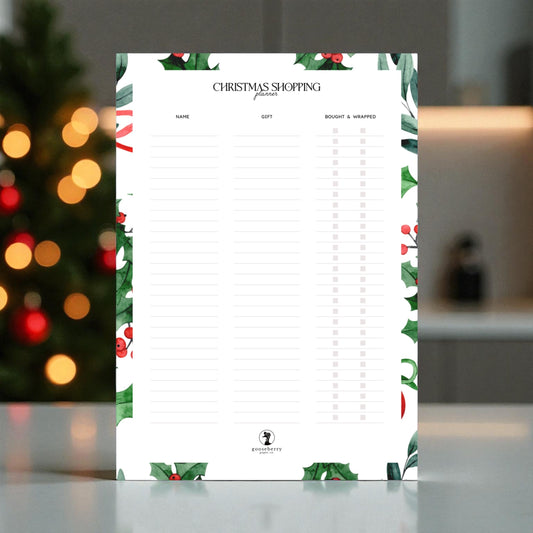 Mockup of blank printable Christmas shopping list with festive border on a blurred background.