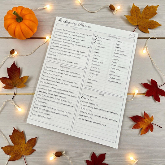 Printable Thanksgiving Organizer sheet on a wooden surface with autumn leaves and lights.